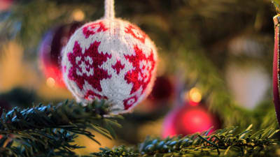 Närbild på en stickad boll i en julgran. 