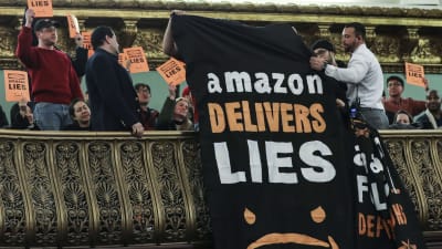 "Amazon levererar lögner" står det på banderollen som vecklades ut från balkongen under höringen med Amazons ledning i New York Stadshus.