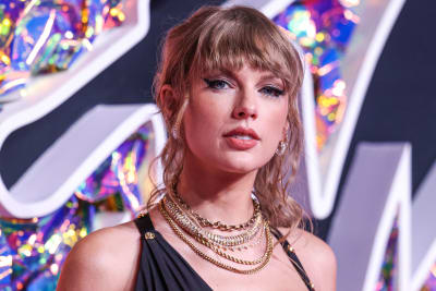 Närbild av Taylor Swift som tittar mot kameran. Hon är klädd i en klänning som lämnar axlarna bara och runt halsen har hon fyra-fem olika halsband.