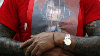 En man håller ett foto av Mynamars fängslade valda ledare Aung San Suu Kyi mot bröstet.