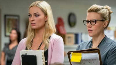 Kayla och hennes kollega står och lyssnar på feedback under ett möte.