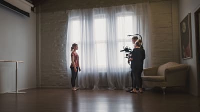 Fotografen Rasmus Tåg och regissören Maria Seppälä står i ett rum tillsammans med en dansös i Taideruukki i Kuusankoski.