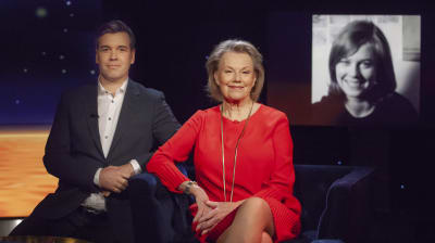 Arja Saijonmaa sitter i röd klänning bredvid Daniel Olin i gråblå kavaj. I bakgrunden ett svartvitt foto på Arja som ung.