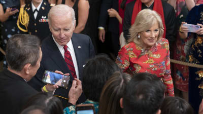 President Joe Biden och hans hustru Jill Biden omgiven av nyfikna människor med mobiltelefoner.