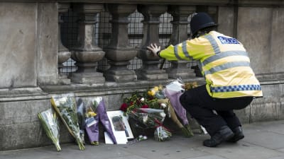 En polis lägger ner blommor vid Whitehall i London.