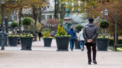 Ett fåtal människor ute på promenad i Esplanadsparken i Helsingfors.