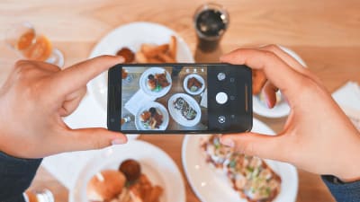 Bild av en telefon som tar en bild av ett bord med mat. 