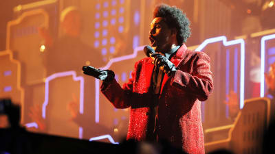 The Weeknd sjunger och dansar på scen. Han är klädd i en rödglittrig jacka.