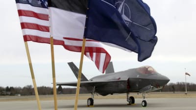 Ett F-35 jaktplan i Estland. I förgrunden står USA:s, Estlands samt Natos flagga.