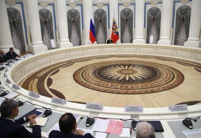 Vladimir Putin istuu Kremlissä ison pyöreän pöydän takana.