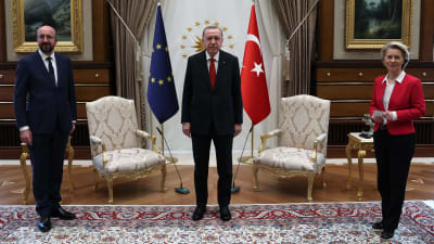 Europeiska rådets ordförande Charles Michel och kommissionens ordförande Ursula von der Leyen tillsammans med Turkiets president Erdogan. I bakgrunden syns EU:s och Turkiets flaggor, samt två stolar. 