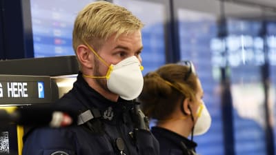 En polis i uniform med ett vitt andningsskydd för mun och näsa.