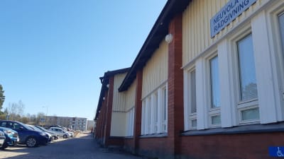 Ett gulmålat större hus, ett affärscenter i Sjundeå. På vägen en skylt som berättar att kommunen har sin rådgivning där.