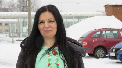 Ruslana Kuisma ute vid Kyrkslätt tågstation. Det snöar. Hon har långt mörkt hår och ler lite.