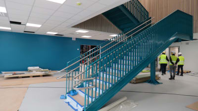 En metalltrappa målad i turkosblått. Väggarna går i samma färg. Biblioteket i det blivande skolcentret i Sjundeå.