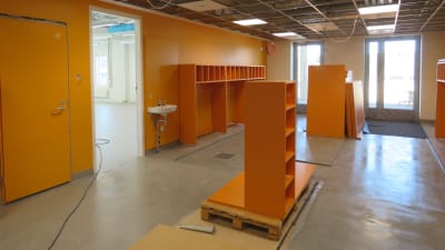 Ett rum för kläder imed orange väggar och skåp. Här ska barn i klasserna 0-2 ha sina ytterkläder och skor.