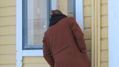 Andreas Rönnberg kikar in i ett fönster i Karis stationshus. Ryggen mot kameran
