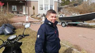 En man står vid sin moped på hemgården i Kapellhamnen i Hangö.