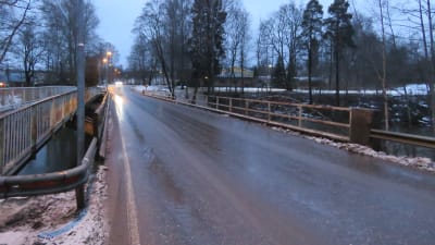 Bron och KArisvägen i Landsbro i Karis, fotat en tidig morgon i januari. Ingen snö, däremot vått och grått. En bil kommer emot.
