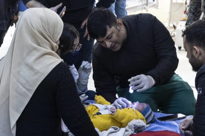 Ett spädbarn undersöks av en akutvårdare i samband med skalvet i Turkiet. 