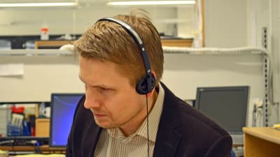 Aarne Kiviniemi lyssnar på en intervju med en arg butiksägare i Tölö.