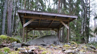 Egilrunstenen, under sitt tak i skogen.