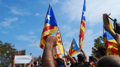 Katalanska flaggor och knytnävar i luften under en demonstration i Barcelona