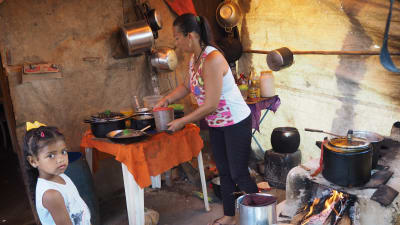 Fattiga landlösa småbönder lagar mat i sitt utekök.