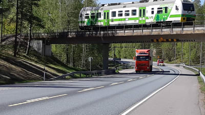 En långtradare kör under en bro i Ekenäs medan en rälsbuss kör på bron.