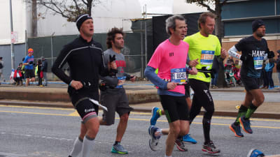 New York City Marathon 2014. En klunga på 5 människor springer i träningskläder på en gata. De har alla lappar med nummer på magen.