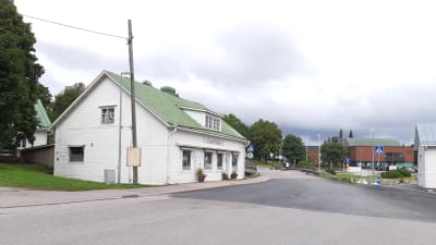 En vit träbyggnad med grönt tak i Ingå kyrkby som kallas laserhuset.