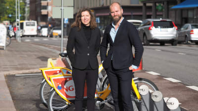 Marianne Weinreich och Lars Strömgren vid en station för gula lånecyklar.