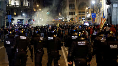 Flera kravallpoliser står med blicken riktad mot hav av demonstranter i centrala Barcelona.