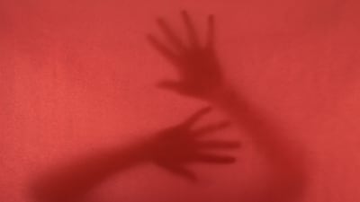 Anonyma händer mot ett rödfärgat fönster.