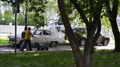 Några män går förbi en gammal bil i en park i Ryssland