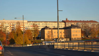 Räcket på Vasklotbron syns. I bakgrunden syns en stor gul byggnad och några höghus.