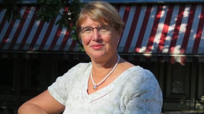 En kvinna med kort blont hår och glasögon ser in i kameran. Marina Holmberg utanför tidningen Västra Nylands redaktion.