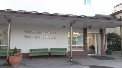 En bild på Raseborgs sjukhus byggnads entre. På väggen står raseborgs sjukhus med silvriga bokstäver