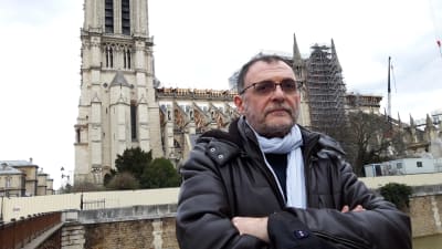 Organisten Yves Castagnet står vid Seinefolden. I bakgrunden syns ruinerna av Notre Dame.