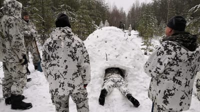Personer med kamouflagekläder gör snögrotta.