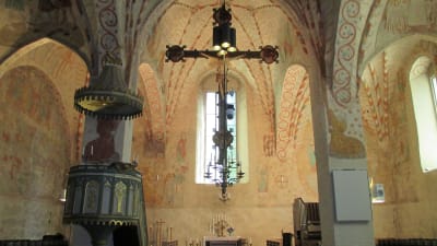 Interiör från Sankt Lars kyrka i Lojo. I förgrunden ses Jesus på korset, i bakgrunden skymtar altaret.