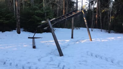 Skadat träningsredskap av trä med traktorspår bredvid på vintern.