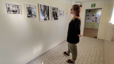 En kvinna står och tittar på fotografier på en vägg.