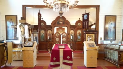Rött och guld dominerar interiören i Hangö ortodoxa kyrka. Kyrkoväggarna är vita.