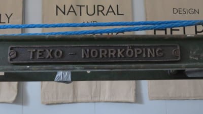 En detalj på en gammal vävmaskin av gjutjärn. Det står märket Texo-Norrköping.
