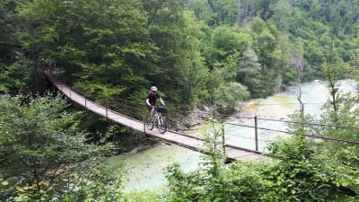 Man cyklar över hängbro över floden Soča i Slovenien.