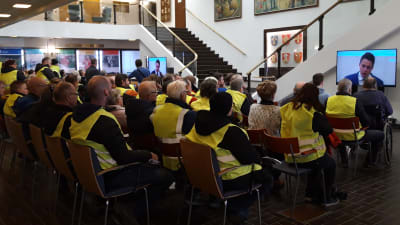 Människor i gula reflexvästar följer med fusionsdebatt i Korsholm.