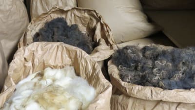 Torr, tvättad fårull i stora bruna papperssäckar.
