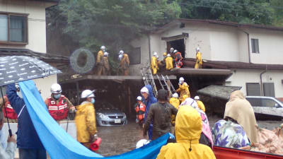 Räddningsarbetare i Nagano där jordskred och översvämningar förstört hus.