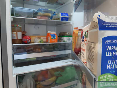 En öppen kylskåpsdörr som visar livsmedlen inuti, mjölk, smör, syltburk, grädde.